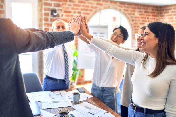 istock Group of business workers standing with hands together at the office 1212742327