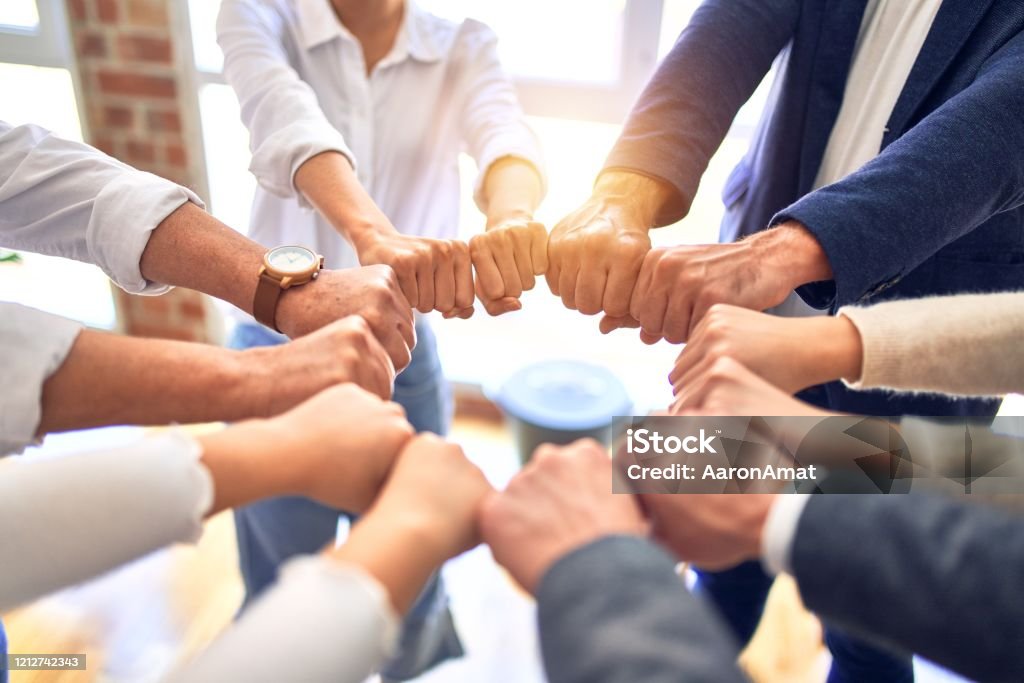 Group of business workers standing bumping fists at the office Teamwork Stock Photo