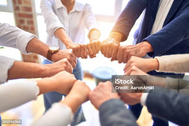 Group Of Business Workers Standing Bumping Fists At The Office Stock Photo - Download Image Now
