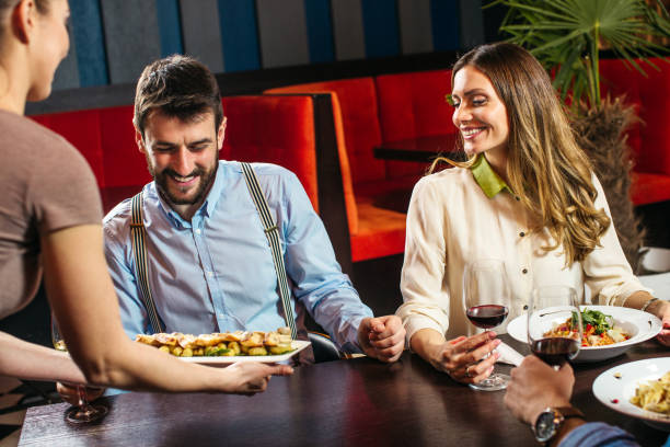 istock Young waitress serving young couple at the restaurant 1212743099