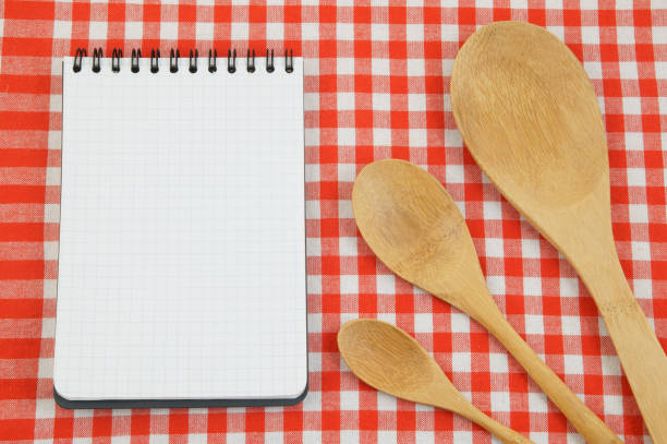 istock Wooden spoons on red tablecloth with blank note pad 1212743137