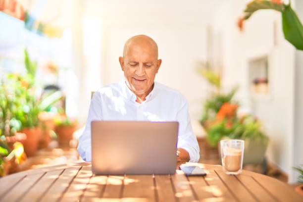istock Senior handsome man smiling happy and confident. Sitting using laptop at terrace 1212743842