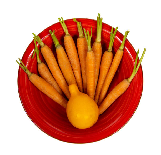istock Lemon and small carrots on a plate isolated on white background 1212745179