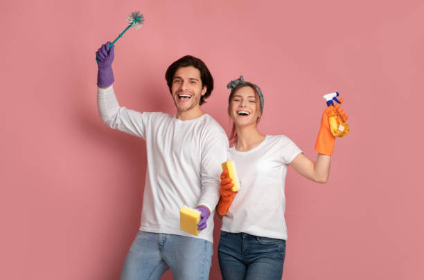 istock Joyful couple with sponge, detergent and brush posing over pink background 1212746987
