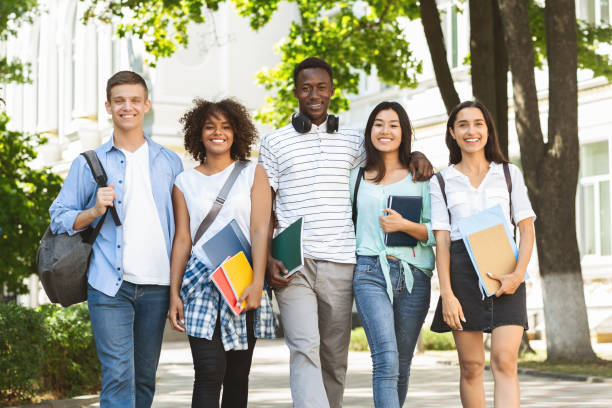 Cheerful college students walking out of campus together, posing outdoors Cheerful college students walking out of campus together, and posing at camera outdoors, having break in classes, free space college students studying together stock pictures, royalty-free photos & images