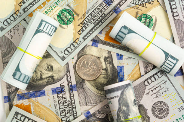 istock Pattern of one hundred dollar bills roll and a quarter dollar coin on a white background 1212748119