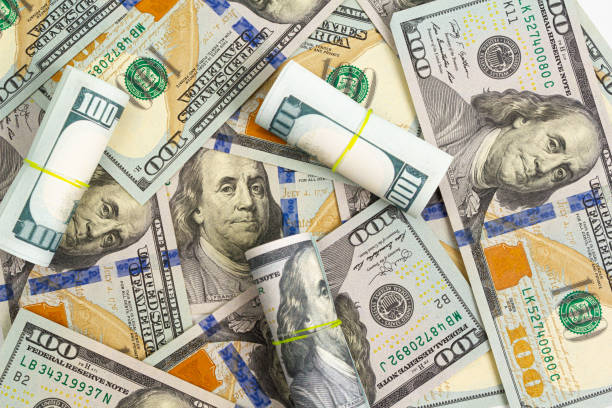 istock Pattern of one hundred dollar bills and rolls on a white background 1212748378