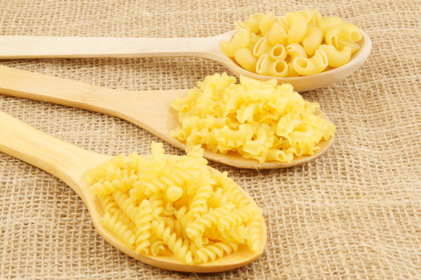 istock Macaroni or pasta in spoons on burlap background 1212755393