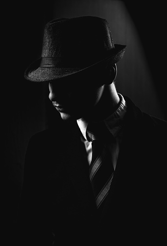 Retro man in hat wears suit and tie, black and white. Noir style.