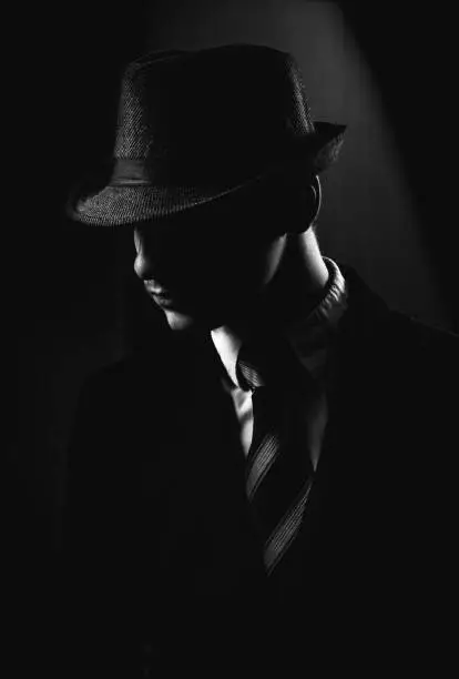 Retro man in hat wears suit and tie, black and white. Noir style.