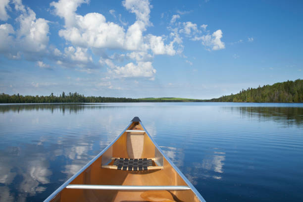 una canoa amarilla se mueve en medio de un tranquilo lago del norte de minnesota por la mañana durante el verano - canoeing canoe minnesota lake fotografías e imágenes de stock