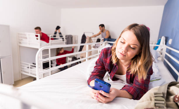istock Girl with phone lying on bed in hostel 1212759206