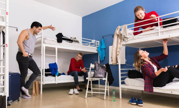 istock Young men and women friendly interacting while staying in modern comfy hostel 1212759213