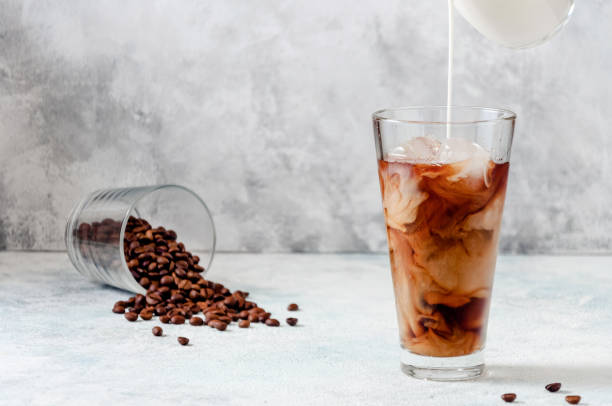 istock Milk Being Poured into Iced Coffee in Tall Glass on Light Grey Background. Concept Refreshing Summer Drink 1212759463