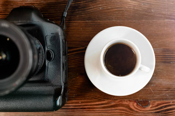 istock Professional digital camera with coffee on wooden table 1212760940