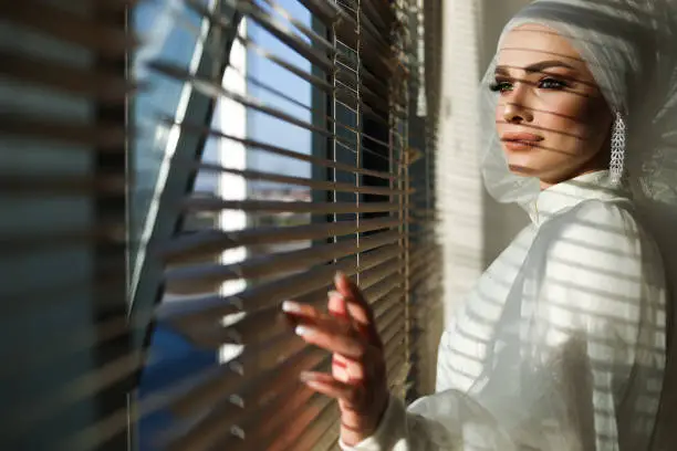 Photo of Portrait Of Muslim Bride Looking Through The Window and Jalousie