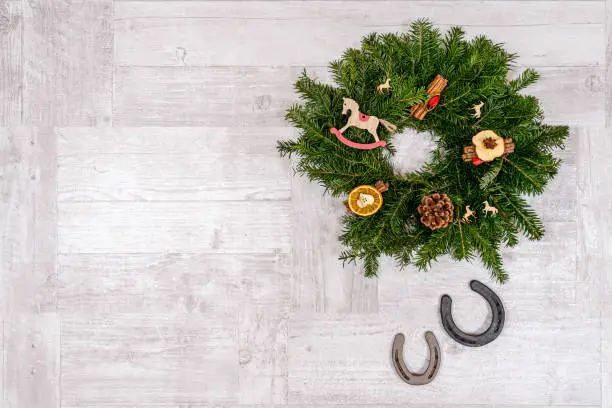 Postcard with horseshoe and horse Christmas decorations on a wooden background. Suitable for horse riding theme greetings, postcards, backgrounds and social media posts just in time for Christmas.