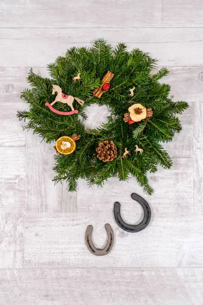 Horseshoe Christmas decorations with horse ornaments on wooden background. Suitable for horse riding theme greetings, postcards, backgrounds and social media posts just in time for Christmas.