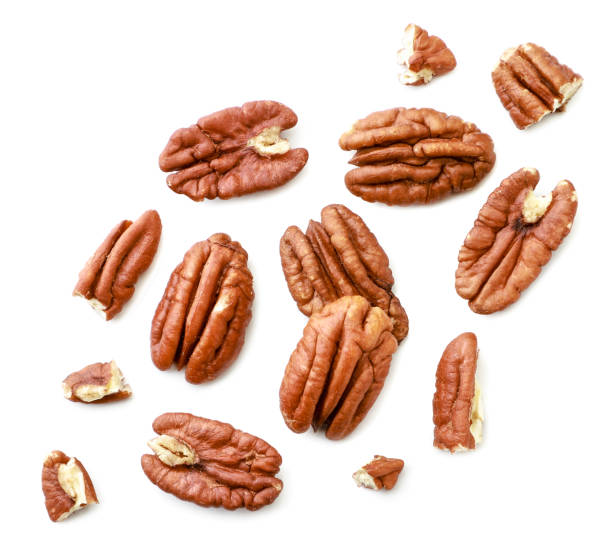 istock Peeled pecans with broken halves and pieces on a white background. The view from top. 1212764194