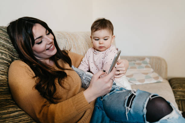 istock Mum checking her smartphone while she's holding her daughter 1212764621