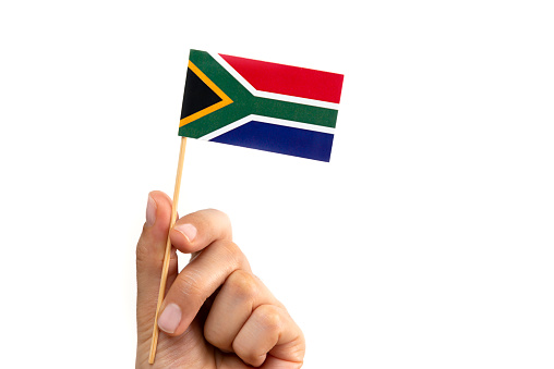 Hand is holding South Africa flag on pure white background.