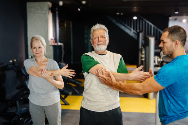 istock Senior couple doing exercises with personal trainer at the gym 1212766554