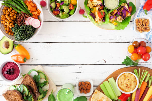 istock Healthy lunch food frame. Table scene with nutritious Buddha bowl, salad, lettuce wraps, vegetables and sandwiches, top view over a white wood background 1212768245