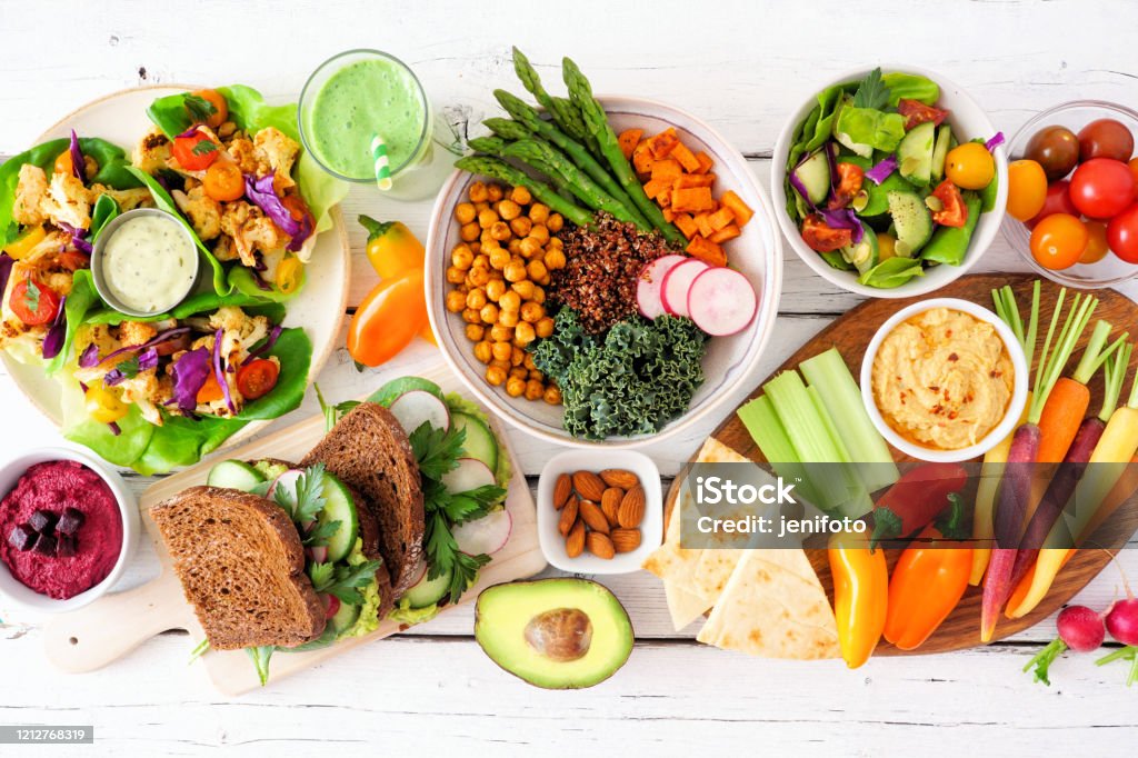 Healthy lunch table scene with nutritious lettuce wraps, Buddha bowl, vegetables, sandwiches, and salad, overhead view over white wood Healthy lunch table scene with nutritious lettuce wraps, Buddha bowl, vegetables, sandwiches, and salad. Overhead view over a white wood background. Healthy Eating Stock Photo