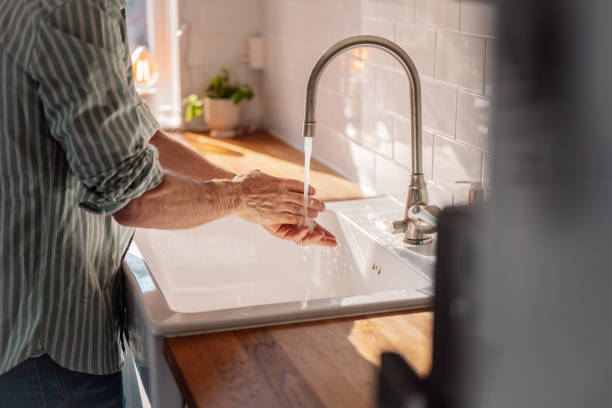 istock Man washing his hands with soap in kitchen sink 1212770252
