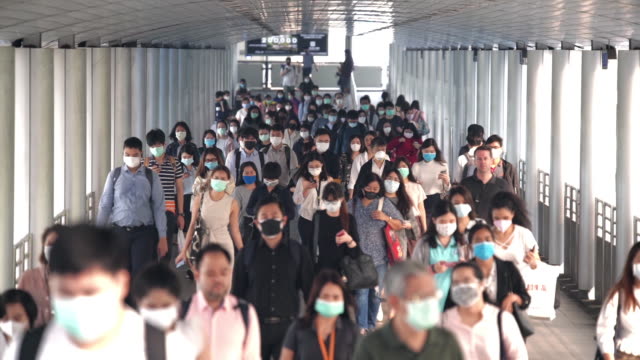 Slow motion scene crowds of Asian people wearing face protection in prevention for Coronavirus or Covid-19 and micro dust pm 2.5 in air while going to their workplace in Bangkok at morning rush hour