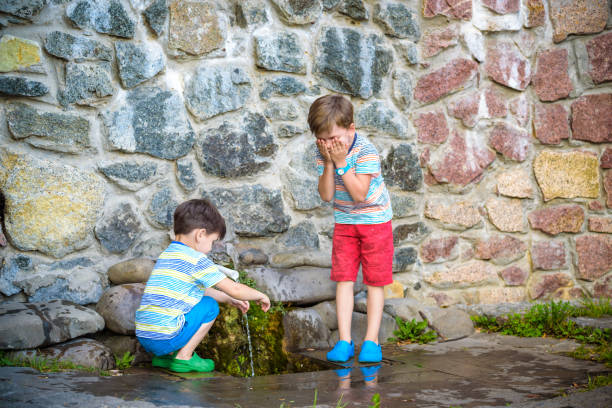 istock the boy drinks cold water outdoors from the pipe 1212771752