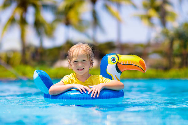 Child in swimming pool on toy ring. Kids swim. Child in swimming pool floating on toy ring. Kids swim. Colorful rainbow float for young kids. Little boy having fun on family summer vacation in tropical resort. Beach and water toys. Sun protection. rainbow toucan stock pictures, royalty-free photos & images