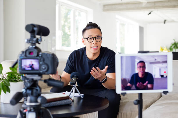 Young man vlogging Handsome asian young man making a video blog. Male vlogger recording content on digital camera. content marketing stock pictures, royalty-free photos & images