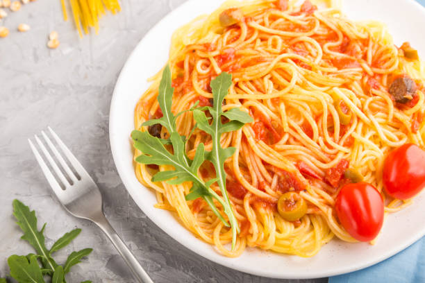 istock Corn noodles with tomato sauce and arugula on a gray concrete background and blue textile. Side view, close up, selective focus. 1212773207