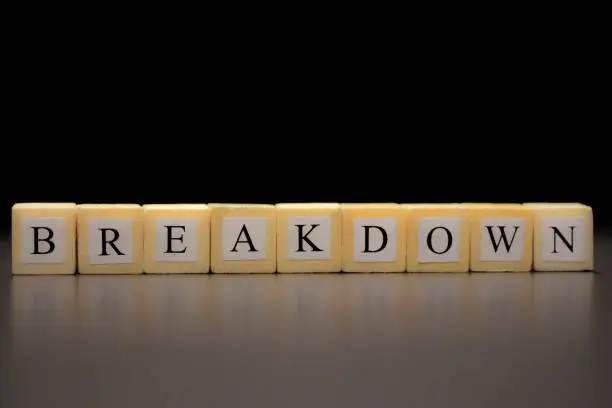 Photo of The word BREAKDOWN written on wooden cubes, isolated on a black background...