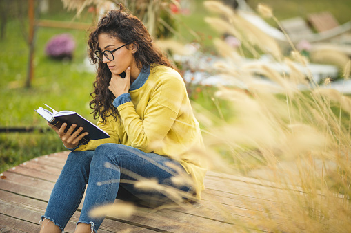 Happy young woman relaxing in nature with book