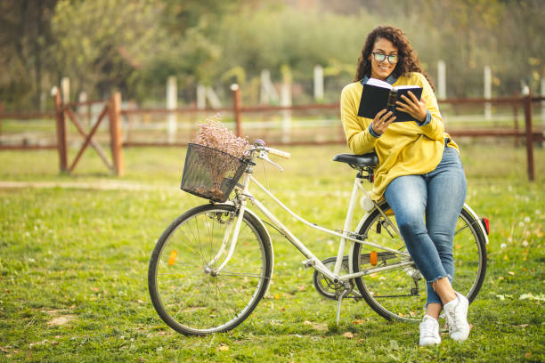 Excited young African American female student with backpack holding open book, studying for test or exam on pink studio background. Education, college, university concept