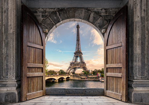 Large wooden door open with Eiffel Tower on Seine River on sunset at Paris, France