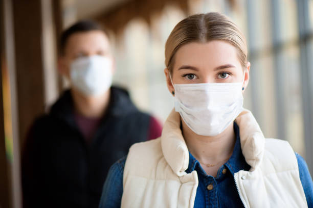 uomo e donna che indossano una maschera protettiva contro le malattie infettive trasmissibili e come protezione contro l'influenza. nuovo coronavirus 2019-ncov dalla cina - safety protective workwear healthcare and medicine healthy lifestyle foto e immagini stock