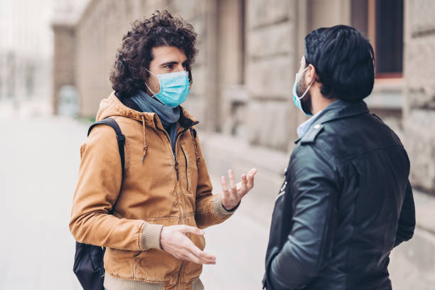 istock Two young men talking on the street during virus epidemic 1212782131