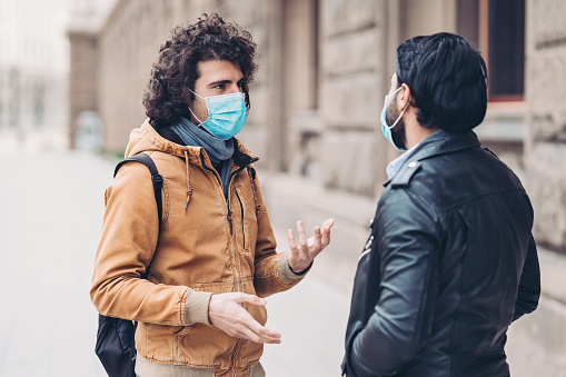Two men with protective masks outdoors in the city