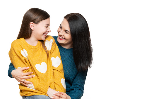 Waist up studio portrait of a mother and young daughter face to face laughing. Happy family laughing background isolated over white.