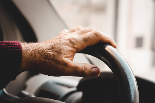 Men's hand on the steering wheel of the car