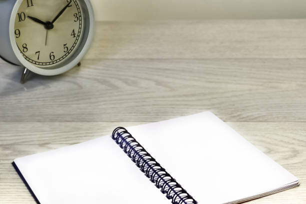 istock Business. Workplace. Alarm clock, and notepad on a wooden table 1212786875