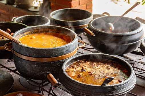 Typical Brazilian foods placed in clay pots and on a metal plate of a traditional wood stove