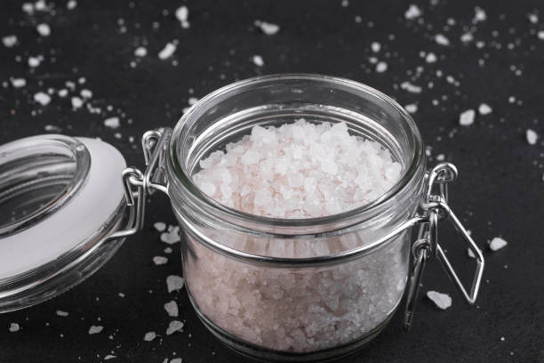 istock Coarse sea salt in a glass jar on a dark background. 1212788968
