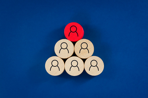 Business concept image of wooden pegs with people icons over blue background, human resources and management concept.