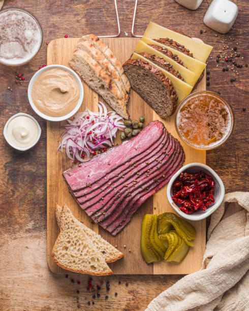 Sliced Deli Pastrami on wooden board, flat lay
