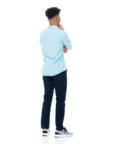 Full length of aged 18-19 years old with curly hair african-american ethnicity teenage boys standing in front of white background wearing pants who is uncertainty