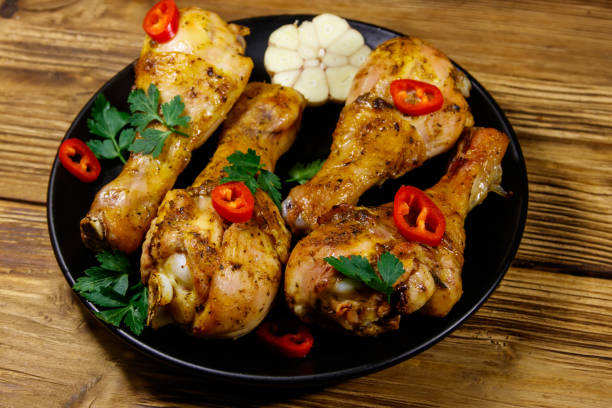 istock Roasted chicken drumsticks with spices in a black plate on a wooden table 1212798008